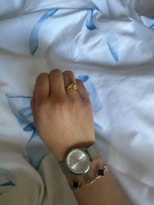 Guldfärgad ring med snäckformad detalj plus lite annat  - Säljer en snygg guldfärgad ring med en unik snäckformad detalj framtill. Sälhwr även en silver klocka från regel och ett armband (HELT ROSTFRITT) med svart klöver och fågel.Säljer allting tillsammans för 170kr. Om du vill köpa enskilt ( armband för 45kr) (silver klocka för 75kr) (ring för 70kr) pris kan diskuteras och ingen av smyckena rostar oavsett vad❤️