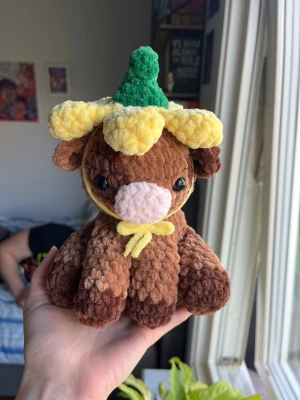 Virkad kossa med blomhatt🌼🐄 - Supersöt virkad kossa som sitter ner med en liten Blom-hatt! Kossan är ljusbrun med mörkbruna fläckar och hatten gul, precis som en liten smörblomma. Hatten är avtagbar, om man önskar att den ska fästas bättre (än bandet under hakan) så är det bara att meddela vid köp!☺️🌼🐄