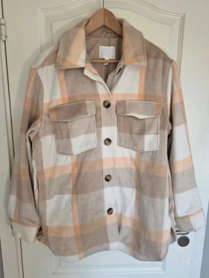 RUTIG JACKA H&M STL. M - VÅRJACKA I NYSKICK   SKJORTJACKA FRÅN H&M  VÅRJACKA  STL M, SOM 42 BYSTMÅTT 128 CM LÄNGD 79 CM FODRAD.  MKT BRA SKICK  SPARSAMT ANVÄND  120 KR + FRAKT     HAR KATT PARFYMFRITT  
