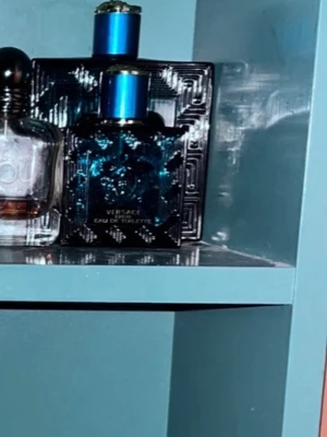 Byte - En elegant parfym från Versace i en fyrkantig, mörkblå glasflaska med detaljerat mönster och blått metallock. Flaskan har en lyxig och modern design som sticker ut i badrumshyllan. Perfekt för dig som gillar exklusiva dofter och snygg förpackning.