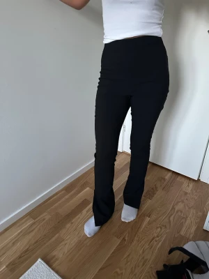 Svarta kostymbyxor med hög midja - Snygga svarta kostymbyxor med hög midja och raka ben. Byxorna har en stilren look och passar perfekt till en dressad outfit. Materialet är mjukt och följsamt för en bekväm känsla hela dagen.