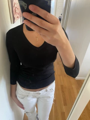 Svart v-ringad topp - Svart långärmad topp med v-ringning och figurnära passform. Enkel och stilren design som passar till mycket. Perfekt att matcha med jeans eller kjol.