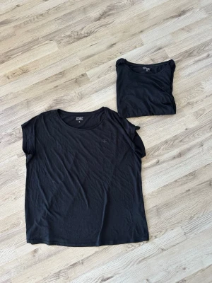 2 Svarta t-shirt från Iconic - Två svarta t-shirts från Iconic i enkel och stilren design. T-shirten har rund halsringning, korta ärmar och en liten logga på bröstet. Tillverkad i mjuk bomull som känns skön mot huden.