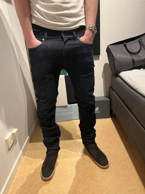 Mörkblå slim fit jeans herr från acne studio - Snygga mörkblå slim fit jeans från acne studio med låg midja och raka ben. Klassisk femficksmodell med svarta sömmar och diskreta detaljer. Jeansen har en modern passform och är tillverkade i stretchigt denimtyg för extra komfort. Modellen är 182 och väger 75 kg
