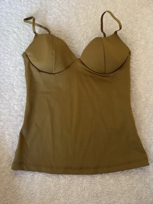 Olivgrön korsettopp från Gina Tricot - Slutsåld snygg olivgrön korsettopp från Gina Tricot med vadderade kupor och smala axelband. Helt ny endast provad.