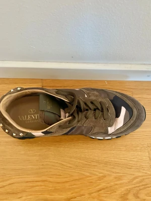 Valentino camo sneakers i mocka -  sneakers från Valentino med kamouflagemönster i grönt, rosa, svart och beige. Ovandel i mocka och textil, med gröna skosnören. Priset kan förhandlas