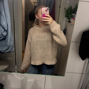 Beige chunky stickad tröja - Mysig beige stickad tröja med grovstickat mönster och avslappnad passform. Tröjan har breda muddar vid ärmslut och nederkant samt en rund halsringning. Perfekt för lager-på-lager och chill dagar.