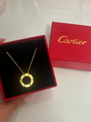 halsband love cirkel  - Snyggt halsband med klassisk Love-cirkel i guldfärg. Hängsmycket är runt med ingraverade detaljer och hänger på en tunn guldfärgad kedja. Kommer i en söt box. Boxen har dock en lätt fläck som knappt syns på vänster framsida🫶🏽