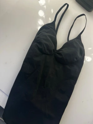 Svart body shapewear från h&m - Aldrig använd!!! bara tvättad och prislappen är av. Snygg svart body med smala, justerbara axelband. Klassisk V-ringning och mjukt stretchigt material som sitter skönt mot kroppen. Storlek S.