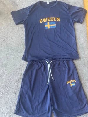 Blått Sweden set med t-shirt & shorts - Mörkblått set med t-shirt och shorts. Båda plaggen har texten 'SWEDEN' de är helt nytt! Ny pris 999kr säljer för 290 kr för setet. 