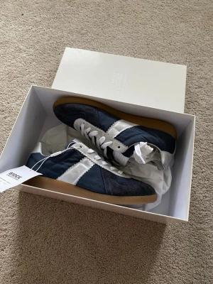 Maison Margiela NFC 25Ss Canvas Special Edition - Nypris 7500 om inte helt slutsålda. Väldigt unika , perfekt för dig som vill sticka ut från alla andra npc gats. Snygga sneakers från Maison Margiela i marinblå mocka och vitt läder med klassiska vita snören och gummisula. Ikonisk design med kontrasterande paneler och låg profil. Perfekta för dig som gillar stilrena och trendiga skor.