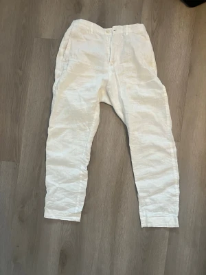 Vita linnebyxor från Zara - Snygga vita linnebyxor. Byxorna har hällor för skärp, dragkedja och knapp framtill samt resår baktill för extra komfort. Perfekta för en avslappnad och stilren look.