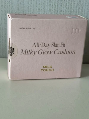 Milk Touch Milky Glow Cushion 24N - Foundation i cushion-format från Milk Touch i nyansen 24N Sand Beige. Ger en mjuk, glowig finish och är lätt att applicera med medföljande svamp. Förpackningen är ljusrosa och rymmer 15g produkt. Perfekt för dig som vill ha en naturlig lyster.
