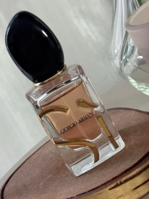 Giorgio Armani Si Eau de Parfum - Elegant parfym från Giorgio Armani i en genomskinlig glasflaska med guldiga detaljer och svart lock. Doften har en varm, bärnstensfärgad vätska och flaskan rymmer 30 ml. Perfekt för dig som gillar lyxiga och stilrena dofter. Fick parfymen som present, men doften passar inte mig. Byter till en annan parfym. Kom med förslag.