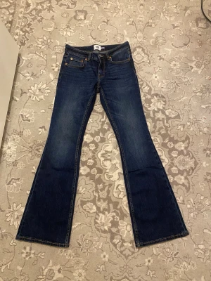 Mörkblå bootcut jeans - Snygga mörkblå bootcut jeans med klassisk femficksdesign och kontrastsömmar. Jeansen har en låg midja och är tillverkade i denim med stretch för extra komfort. Perfekt för dig som gillar en tidlös och trendig look.