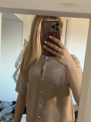 Beige kofta med pärlknappar - Kortärmad beige/ljusbrun kofta med fina pärlknappar framtill.  Enkel och stilren design som passar till mycket. Använd 1-2 gånger. Storlek XS💗