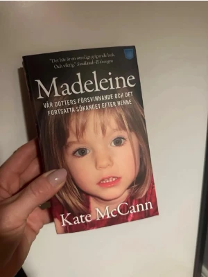 Madeleine av Kate McCann - En gripande pocketbok med svart och vinröd framsida, skriven av Kate McCann. Boken handlar om försvinnandet av Madeleine och föräldrarnas fortsatta sökande. Omslaget har tydlig titel och författarnamn i vitt, samt ett foto på framsidan.