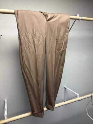 Beige kostymbyxa från Zanella (ord pris ~4500kr) - Ord pris: 3500kr - 5000kr. Snygga beige kostymbyxor från Zanella med klassisk rak passform och pressveck. Byxorna har diskret uppvik vid benslut och är tillverkade i ett slätt material som ger en stilren look. Perfekta för dig som vill ha en clean och elegant stil. Lite skrynkliga på bilden men rättar man lätt till med en strykning. Passar mig bra, kanske lite pösiga (för jag har smala ben). Men jag är 191cm och väger 87kg ungefär. Med långa ben. 