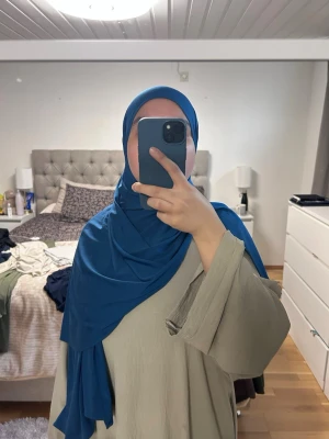 Blå sjal i premium jersey - Snygg blå sjal i ett mjukt och följsamt tyg. Sjalen är rektangulär och har en stilren, enkel design utan mönster. Perfekt att styla på olika sätt för en personlig look. Premium jersey från Hijab kompaniet , knappt använd 