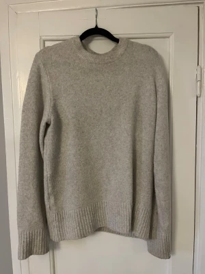 Beige stickad tröja  - Mysig beige stickad tröja med rund halsringning och ribbade muddar vid ärmslut och nederkant. Tröjan har en rak passform och är perfekt för lager-på-lager. Nästan aldrig använd.