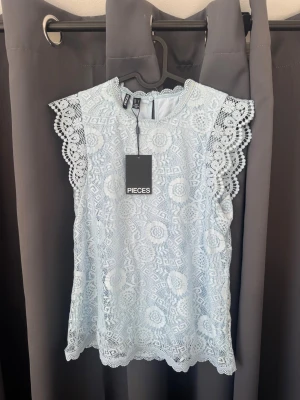 Ljusblå spetsblus från Pieces - Säljer en helt oanvänd blus från pieces som är köpt förra året. Blusen är jättesöt och har fina detaljer men är inte riktigt min smak därav säljer jag den. Nypris: 299kr🩵