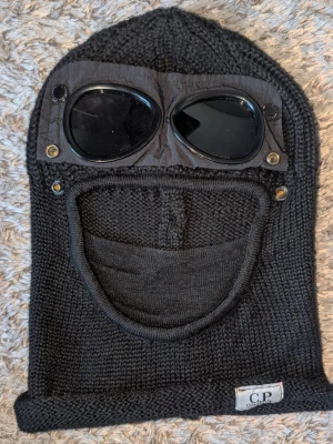 Svart C.P. Company balaclava  - Säljer en svart stickad balaclava från C.P. Company med glasögon som går att knäppa över ögonen, skriv vid intresse så löser vi allt tillsammans 😄