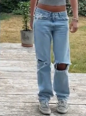 Ljusblå jeans med hål - Säljer ett par ljusblå jeans med raka ben och hål över knäna. Jeansen har låg midja. Perfekta för en avslappnad och trendig look💓💓