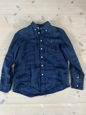 Ralph lauren linne skjorta L 14-16 - Säljer denna mörkblåa Ralph lauren linneskjorta. Jättefint skick och skön. Storlek L i barnstorlek, motsvarar ungefär xs i herr. Skriv om ni har frågor!
