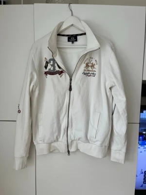 Fullzipp La Martina - Vit fullzipp tröja från La Martina som är ruggigt snygg. Säljer pga att den är för liten. Passar någon som är runt 180. Storlek M. Inga defekter. Hör av er vid intresse kan gå ner i pris vid snabb affär!