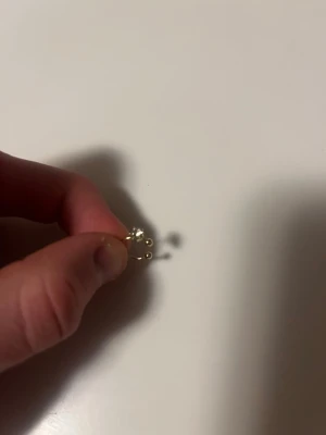 Guldörhänge med små pärlor - Sött örhänge i guldfärgad metall med tre små vita pärlor i rad. Minimalistisk och trendig design som passar perfekt till din smyckessamling. Perfekt för dig som gillar stilrena detaljer.