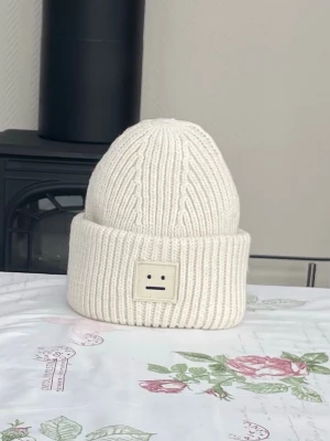 Acne mössa - Säljer en vit ribbstickad mössa från Acne Studios med uppvikt kant. Jättefin i 100% ull. Varsamt använd utan fläckar eller skador. Ej krympt i tvätt. Jättefin eftertraktad populär mössa. Skickar snabbt🤍✨