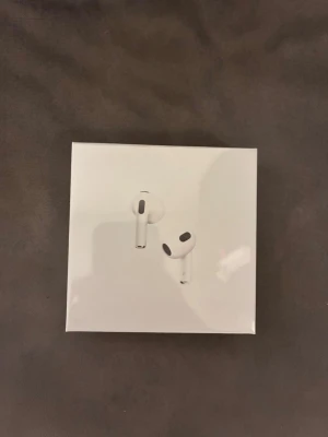 Apple AirPods med MagSafe-laddning - Säljer ett par vita Apple AirPods med MagSafe-laddningsetui. Trådlösa in-ear hörlurar i stilren design med rundade former och diskreta svarta detaljer. Perfekta för musik, samtal och vardagsbruk. Levereras i originalförpackning.