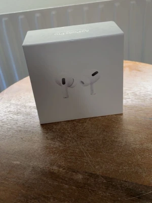 Apple AirPods Pro med laddningsetui - Säljer ett par Apple AirPods Pro i vitt med trådlöst laddningsetui. De har en stilren och kompakt design med silikonproppar och brusreducering. Perfekta för musik, samtal och träning. Levereras i originalförpackning.