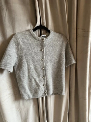 Grå kortärmad kofta från Zara - Super skön kofta med fina knappar från Zara. Tröjan är i storlek M men skulle säga att den är liten i storleken💗