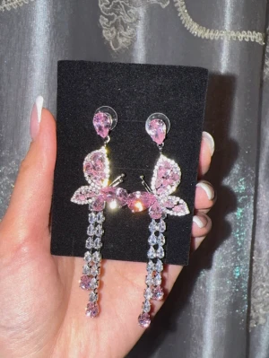 Starlit Butterfly Drop Earrings  - Säljer dessa eleganta och romantiska örhängen från Aurora Pink. Helt oanvända och i nyskick.  Vackra rosa kristaller i fjärilsdesign med gnistrande detaljer och långa hängande stenar som fångar ljuset otroligt fint ✨  Perfekta till fest, bröllop, middag eller när du vill känna dig extra fin 💕  Allergivänliga och bekväma att bära. En perfekt present – eller en liten lyx till dig själv. 