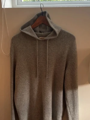 Stickad hoodie  - Mysig stickad hoodie i en neutral grå färg med huva och dragsko. Perfekt för en avslappnad stil och passar bra till jeans eller mjukisbyxor. Materialet känns mjukt och skönt mot huden. Enkel och stilren design utan synliga loggor. Från these glory days