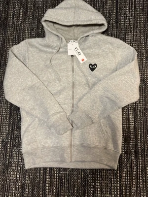 Comme des garçon zip up  - Säljer nu min gråa comme des garçon zip up. Mycket skön bummul mjuk på insidan och sitter mycket bra. Helt ny och inga skador eller smuts på den! 