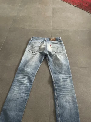 Levi's ljusblå raka/slim jeans - Säljer ett par klassiska ljusblå jeans från Levi's med raka ben och snygg slitning. Jeansen har fem fickor, läderpatch bak i midjan och den ikoniska röda Levi's-lappen på bakfickan. Perfekta för en avslappnad och trendig look. Sjuk wash 🧼!!! Priset är inte hugget i sten!! 🪨 