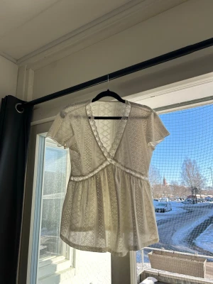 Vit spetsblus med omlott och spetsdetaljer - Söt vit blus i spets med omlott framtill och dekorativa spetskanter. 