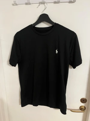 Svart sport  t-shirt från Ralph Lauren - Svart sport t-shirt från Ralph Lauren med den ikoniska vita logobroderingen på bröstet. T-shirten har rund halsringning och korta ärmar. 