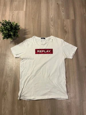 Vit t-shirt från Replay med rutig logga - Säljer nu en Vit Replay T-shirt i storlek Herr S. Den är i väldigt fint skick. Väldigt skönt matrial, mjuk och härligt. Tröjan har ett snyggt rött tryck över bröstet som är väldigt unikt. Det är även ett R som står för Replay uppe vid kragen som är en snygg detalj. Som vanligt tveka inte och höra av dig  Skickar inom 24timmar som vanligt 🚚😉