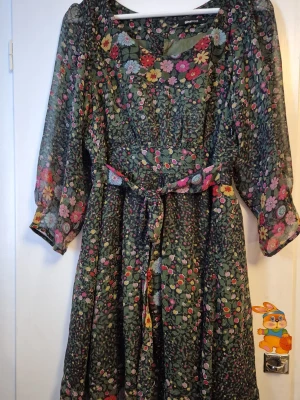 Grön blommig klänning - Grön blommig klänning med knappar på baksidan. Storlek 38