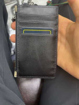 Gucci korthållare med ormprint - Snygg korthållare från Gucci i svart läder på ena sidan och klassiskt GG-mönster med röd och vit orm på andra sidan. Har flera kortfack och en dragkedjeficka med nyckelring. Perfekt för dig som vill ha både stil och funktion.