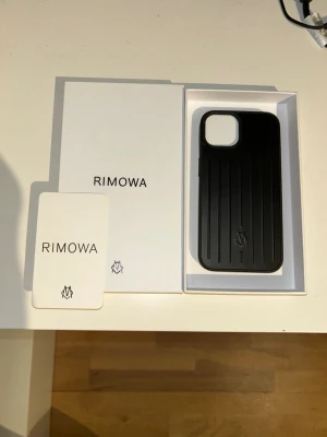 R1mowa mobilskal till iPhone 14 - Snyggt svart mobilskal från R1mowa med klassisk räfflad design och diskret logotyp längst ner. Skalet är tillverkat i ett tåligt material och har en stilren, modern look som passar perfekt till din mobil. Levereras i originalförpackning. Oanvänd och i perfekt skick. Priset kan diskuteras vid snabb affär 