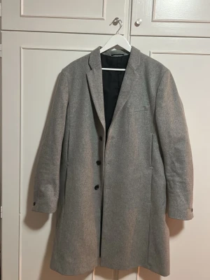 Ljusgrå ullkappa från Filippa K - Stilren ljusgrå kappa i ullmix med klassisk krage och tre knappar framtill. Nypris: 6000 kr Skick: använd ett fåtal gånger 