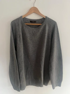 Grå stickad tröja Oscar Jacobson - Snygg grå stickad tröja i ull från Oscar Jacobson med rund halsringning. Storlek XL men kan även passa någon som bär L