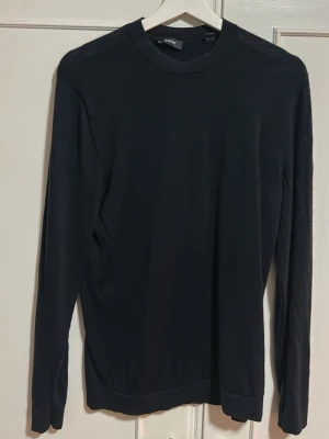 Svart stickad tröja från Esprit  - Klassisk svart stickad tröja från Esprit med rund halsringning och långa ärmar. Tröjan har en enkel och stilren design, perfekt att matcha med olika outfits. Materialet ser ut att vara mjukt och tunt, vilket gör den skön att bära.