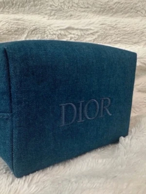 Blå denim necessär från Dior beauty, sminkväska - Ny oanvänd. 15*10*9cm. Snygg necessär från Dior i blått denimtyg med broderad logga framtill. Väskan har en silverfärgad dragkedja med en cool stjärnformad Dior-berlock. Perfekt för smink eller småprylar, och ger en trendig touch till din look.