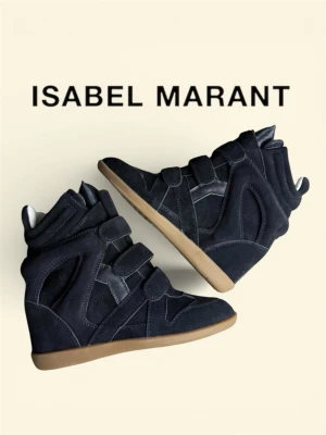 Isabel Marant svarta sneakers med kilklack - Svarta sneakers från Isabel Marant med kilklack och kardborreband. Skorna har en cool design i mocka och läderdetaljer samt en brun gummisula. Perfekta för dig som vill ha en edgy och trendig look. Har dock ingen box kvar så lite minus men annars är allt i jätte bra skick:)