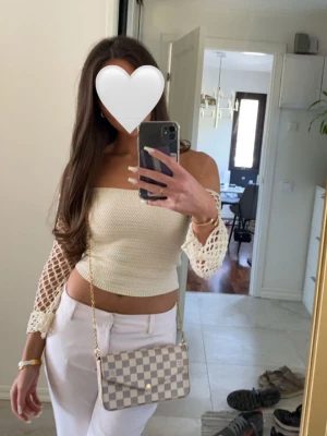 Off shoulder stickad topp från ZARA - Trendig off shoulder stickad topp från ZARA i krämvit färg. Toppen har långa, nätstickade ärmar med knytband vid axlarna och en åtsittande kropp i mjukt material. Perfekt för dig som vill ha en unik och snygg stickad topp till din garderob.